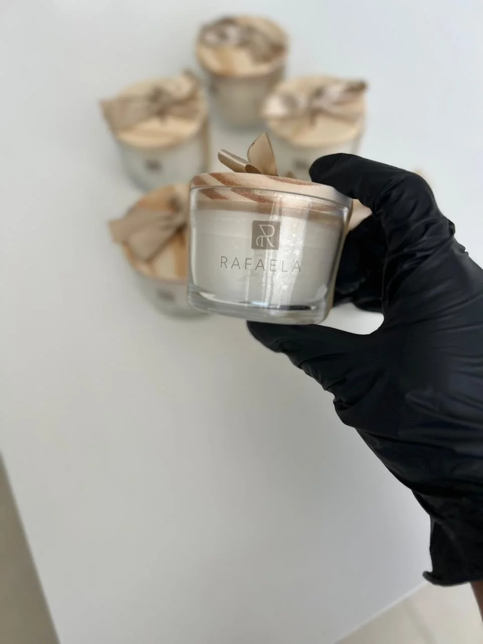 Vela aromática Zane segurada em luva branca — proximidade da pele e fragrância discreta de pele